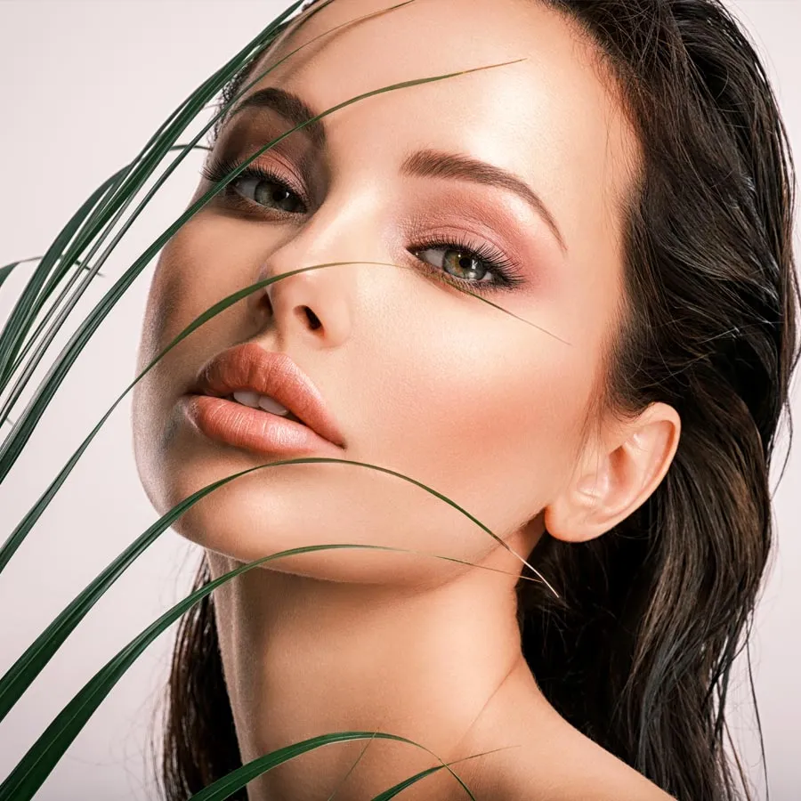 Young beautiful woman with green leaves near face and body. Skin care beauty treatments concept.